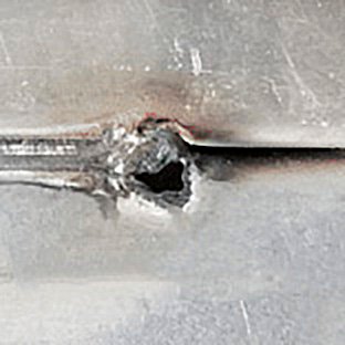 Defeito de solda a laser do tipo trespassado consiste num furo que atravessa o material.